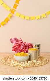 Tasty corn with popcorn and bundle bag on color background. Festa Junina (June Festival) celebration