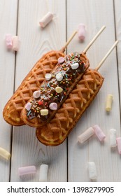 Tasty cornmeal dessert sticks on wooden background. Sweet biscuits decorated with marshmallows and sugar sprinkles.
