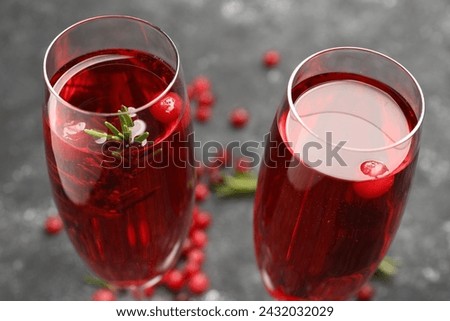 Tasty cranberry cocktail with rosemary in glasses on gray background, closeup