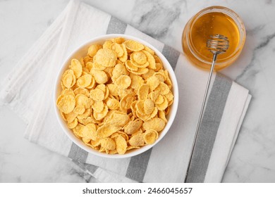 Tasty crispy corn flakes in bowl and honey on white marble table, flat lay. Breakfast cereal - Powered by Shutterstock