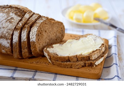 Tasty cut multigrain sourdough bread with fresh butter on a white wooden table. - Powered by Shutterstock