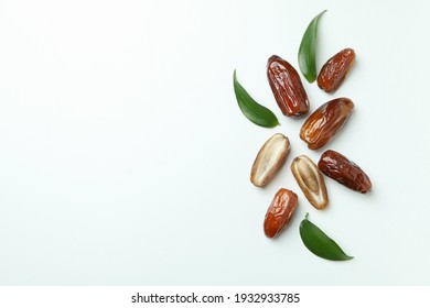 Tasty dried dates with leaves on white background