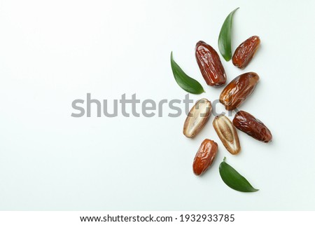 Tasty dried dates with leaves on white background