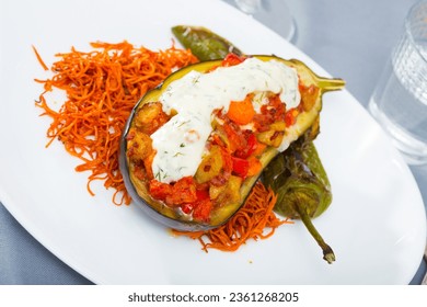 Tasty eggplant stuffed with baked vegetables in sauce served with carrot chips on plate - Powered by Shutterstock