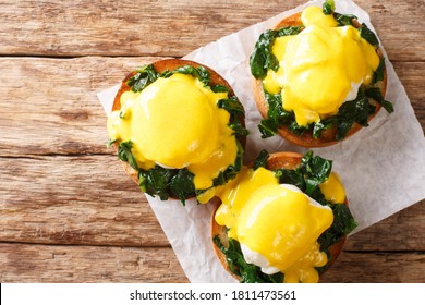 Tasty Eggs Benedict With Spinach And Hollandaise Sauce On A Toasted Bun Close-up On The Table. Florentine Eggs. Horizontal Top View From Above
