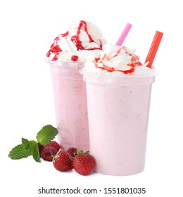 Tasty fresh milk shakes in plastic cups with ingredients on white background