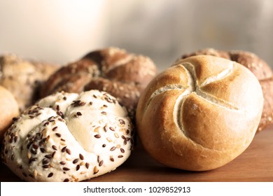 Tasty freshly baked butter kaiser roll  with linseed and sunflower seeds. Top view, copy space, selective focus. Pastries on a wooden table. Blurred background.  Concept of fresh pastry.    
