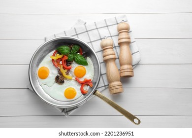 Tasty Fried Eggs With Vegetables In Pan And Spice Shakers On White Wooden Table, Flat Lay