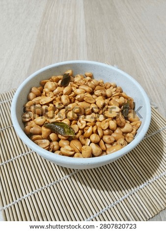 Tasty fried nuts for Eid al-Fitr celebration, served in a simple bowl on a bamboo mat