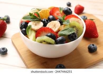 Tasty fruit salad in bowl and ingredients on wooden table, closeup - Powered by Shutterstock