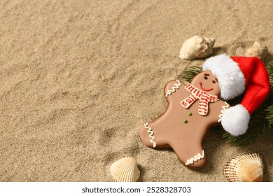 Tasty gingerbread cookie with Santa hat, fir twigs and sea shells on sand background - Powered by Shutterstock