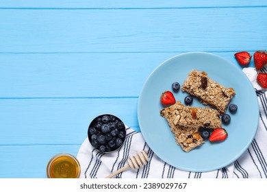 Tasty granola bars with berries and honey on light blue wooden table, flat lay. Space for text - Powered by Shutterstock