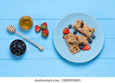 Tasty granola bars with berries and honey on light blue wooden table, flat lay - Powered by Shutterstock