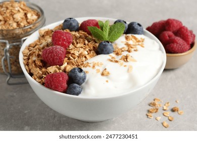 Tasty granola with berries and yogurt in bowl on grey textured table, closeup - Powered by Shutterstock