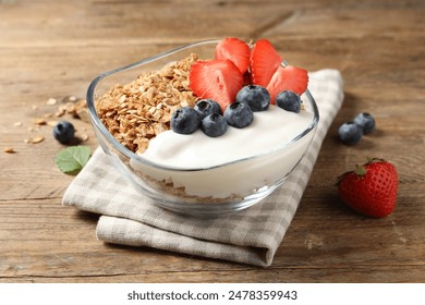 Tasty granola with berries and yogurt in bowl on wooden table, closeup - Powered by Shutterstock