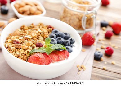 Tasty granola with fresh berries on brown wooden background