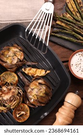 Tasty grilled artichokes on wooden table, flat lay - Shutterstock ID 2368694161