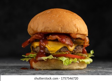 Tasty grilled beef burger with fried bacon and eggs, cheese, tomatoes and lettuce. - Powered by Shutterstock