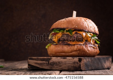 Tasty grilled burger with lettuce and mayonnaise ,on a rustic wooden table of counter, with copyspace
