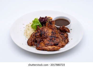 Tasty grilled ckicken chop served on a white plate with sides rice and black pepper sauce - white background
