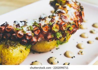 Tasty Grilled Galician octopus leg with roasted potatoes and garlic aioli on wooden table