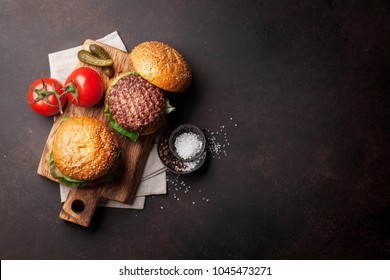 Tasty grilled home made burgers with beef, tomato, cheese, cucumber and lettuce. Top view with copy space - Shutterstock ID 1045473271