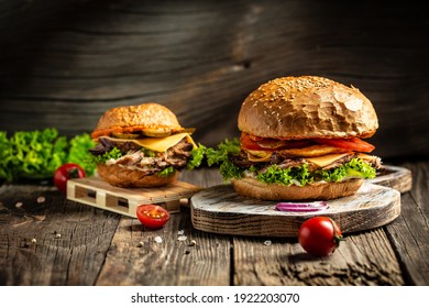 Tasty grilled homemade burgers with beef, tomato, cheese, bacon and lettuce on rustic wooden background. fast food and junk food concept. - Shutterstock ID 1922203070