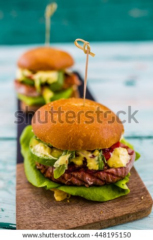 Tasty grilled tuna burger with lettuce and mayonnaise served on wooden table
