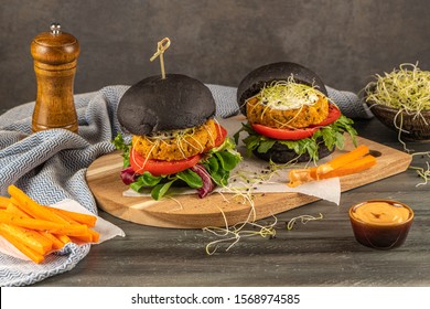 Tasty grilled veggie burger with chickpeas and vegetables on black bread on wooden background