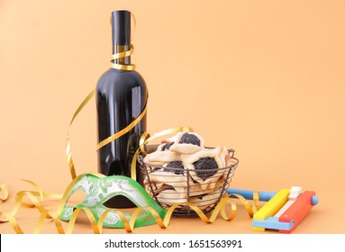 Tasty Hamantaschen, Gragger And Party Decor For Purim Holiday And Bottle Of Wine On Color Background