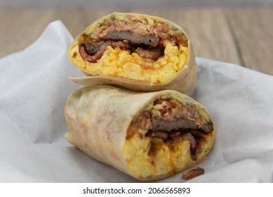 Tasty And Hearty Steak And Eggs Breakfast Burrito Cut In Half To Show The Bursting Ingredients.