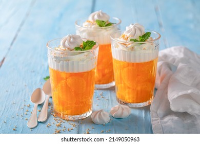 Tasty and homemade orange jelly served with meringue and whipped cream. Mandarins jelly with whipped cream.