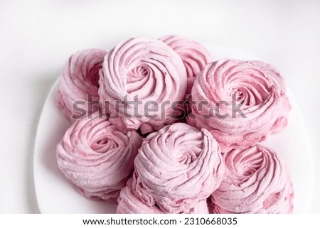 tasty homemade zephyr marshmallows with blackberries taste inside whisk wires or in fork,black gray tiles background,kitchen towel.tea in cup and kettle,marshmallow on plate.close up texture macro