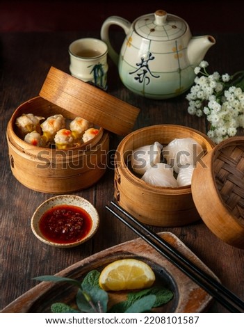 Tasty and hot chinese dumplings on a table beautifully decorated with tea pot and flowers. Dim Sum Chinese food.Top view.