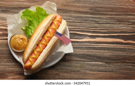 Tasty Hot Dog With American Flag On Table