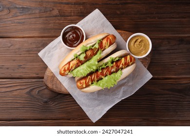 Tasty hot dogs with lettuce, ketchup and mustard on wooden table, top view - Powered by Shutterstock