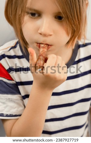 Tasty intermission: A long-haired 10-year-old takes a break, savoring a sausage snack