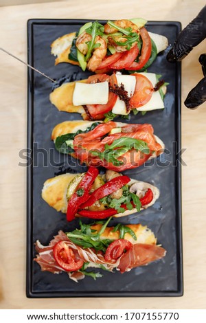 Tasty italian appetizer bruschettes with tomatoes anchovies prosciutto, mozarella, shrimps and seafood
