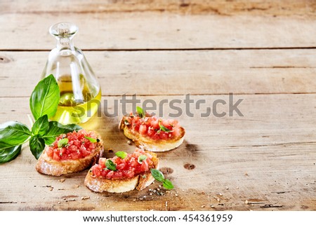 Tasty Italian tomato bruschetta with olive oil on toasted slices of baguette served with fresh basil on a rustic wooden table with copy space Stock photo © 