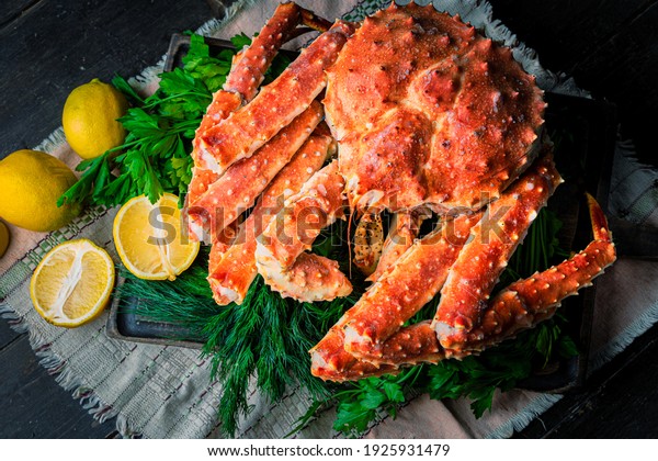 Tasty\
king kamchatka crab with lemon slices on wood\
board
