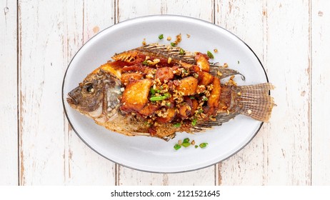 Tasty Large Fried Nile Tilapia Fish With Garlic And Chili In Oval Ceramic Plate On White Wooden Texture Background, Top View, Flat Lay, Light And Airy Food Photography