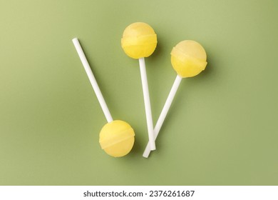 Tasty lollipops on green background, flat lay