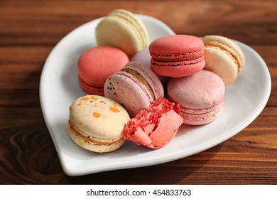 Tasty macaroons in heart shape plate on wooden background - Powered by Shutterstock