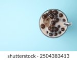 Tasty milk bubble tea in glass on light blue background, top view. Space for text