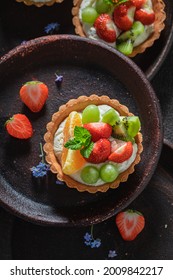 Tasty mini tart with strawberries and grapes. Sweet summer dessert. Tart with cream and fruit.