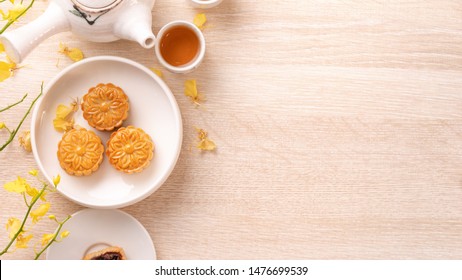 Tasty Moon Cake For Mid-Autumn Festival On Bright Wooden Table, Concept Of Festive Afternoon Tea Decorated With Yellow Flowers, Top View, Flat Lay.