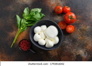 Tasty mozzarella cheese with basil and tomatoes in black bowl, ingredients for salad Caprese. on old rustic metal background. Caprese salad ingredients. Selective focus. top view flatlay - Powered by Shutterstock