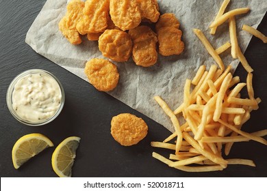 Tasty nuggets with fries and sauce on table