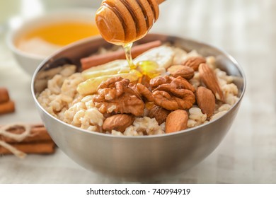 Tasty oatmeal with honey and nuts in bowl, close up - Powered by Shutterstock