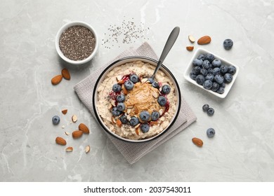 Tasty oatmeal porridge with toppings served on light grey table, flat lay